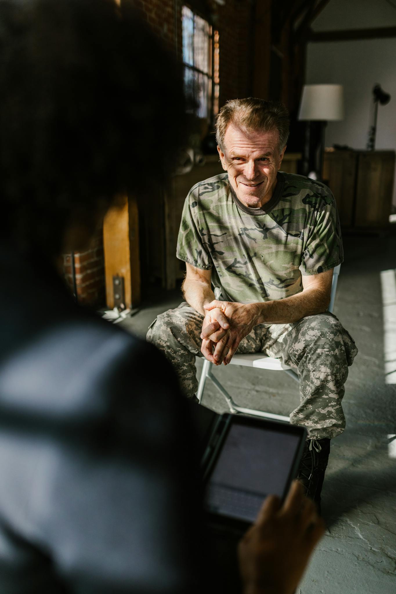 A senior military veteran discussing with a therapist in a bright room.